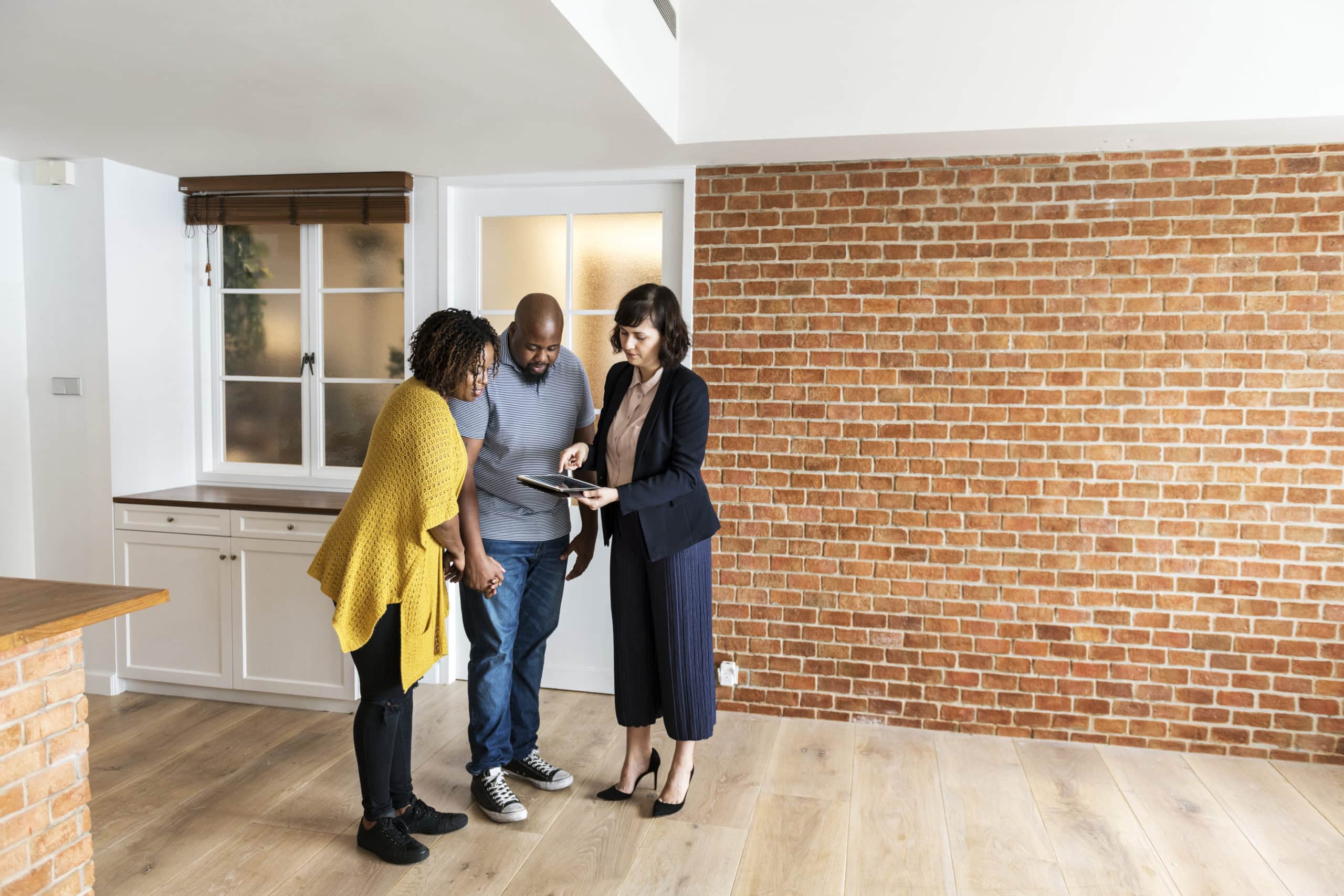 Couple visitant un logement vide avec une agente immobilière