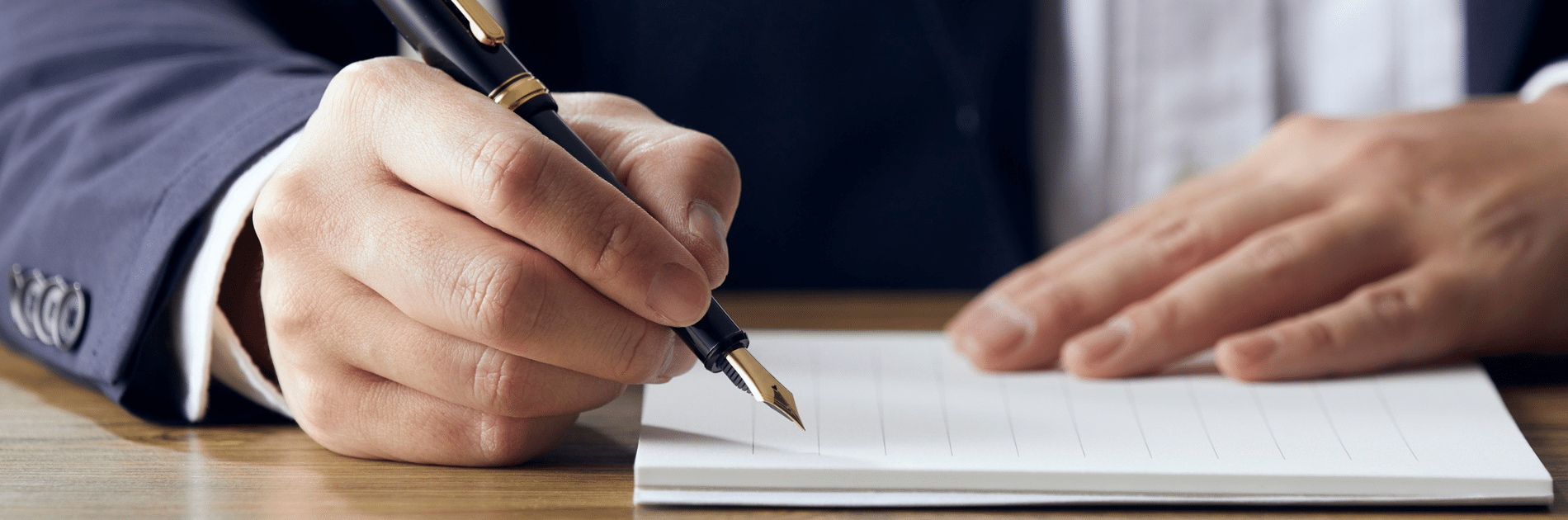 Main écrivant au stylo plume sur un carnet