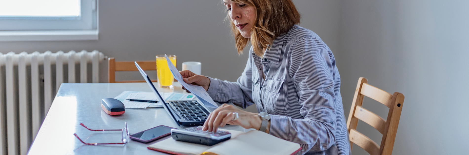 Femme faisant ses comptes à table avec ordinateur et calculatrice