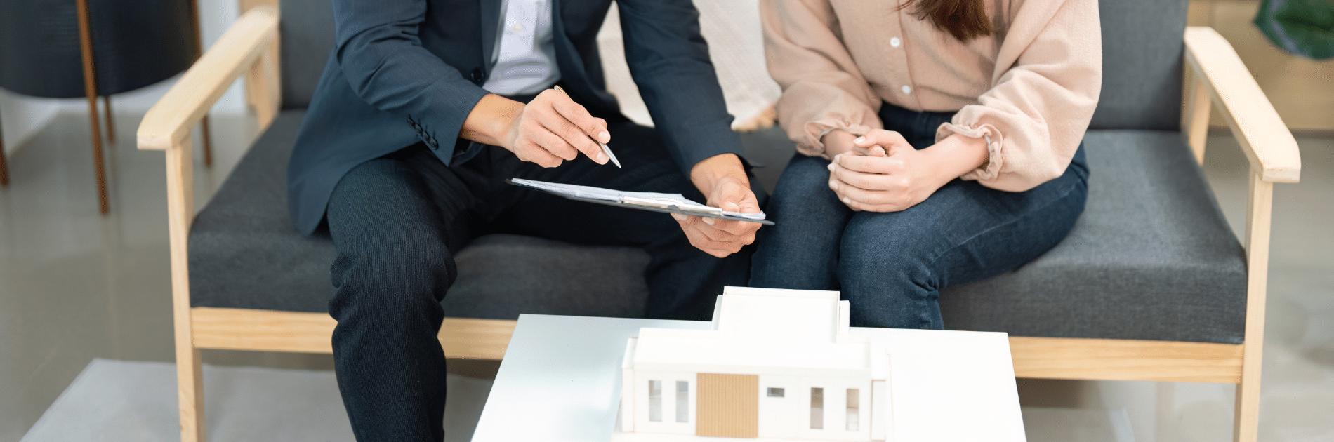 Conseiller présentant un document à une cliente, maquette de maison sur la table