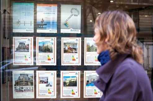 Femme regardant les annonces immobilières dans la vitrine d’une agence